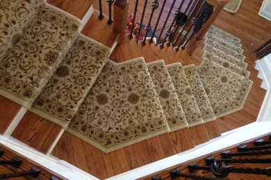 Large elegant wooden curved wood railing staircase photo in New York with painted risers