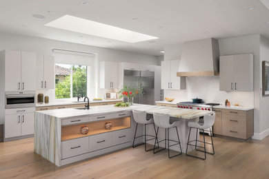 Example of a large trendy u-shaped light wood floor and brown floor eat-in kitchen design in San Diego with an undermount sink, flat-panel cabinets, gray cabinets, marble countertops, white backsplash, porcelain backsplash, stainless steel appliances, an island and white countertops
