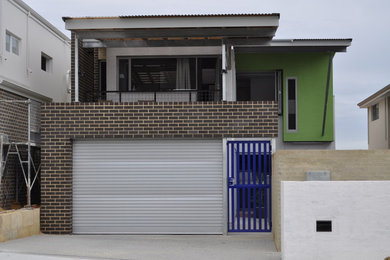 Photo of a mid-sized contemporary two-storey brick green exterior in Perth with a flat roof.