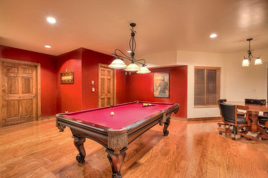 Example of a walk-out medium tone wood floor basement design in Albuquerque with red walls