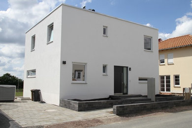 Mittelgroßes, Zweistöckiges Modernes Einfamilienhaus mit Putzfassade, weißer Fassadenfarbe und Flachdach in Frankfurt am Main