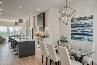 Example of a transitional light wood floor open concept kitchen design in Calgary with an undermount sink, shaker cabinets, white cabinets, quartzite countertops, gray backsplash, ceramic backsplash, stainless steel appliances and an island