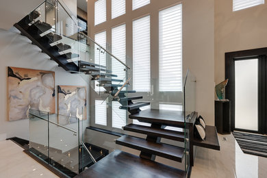 Photo of an expansive modern wood floating staircase in Edmonton with glass railing.