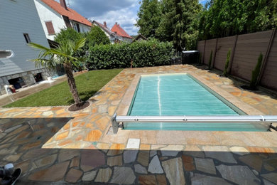 Imagen de piscina mediterránea de tamaño medio rectangular en patio trasero con adoquines de piedra natural