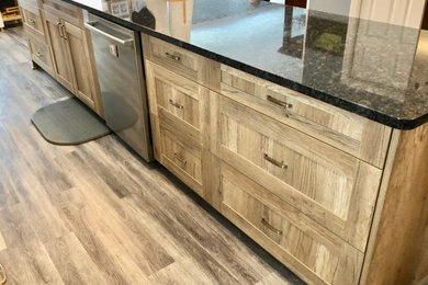 Inspiration for a large rustic vinyl floor and brown floor open concept kitchen remodel in Other with a double-bowl sink, shaker cabinets, light wood cabinets, granite countertops, stainless steel appliances, an island and black countertops