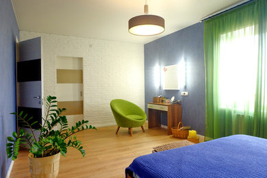 Modelo de dormitorio principal escandinavo grande con paredes azules, suelo laminado y suelo marrón