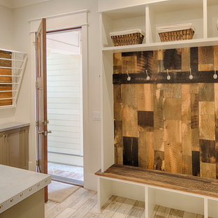 Modelo de lavadero multiusos y en L, de estilo de casa de campo, de tamaño medio, con fregadero encastrado, armarios con paneles empotrados, puertas de armario beige, paredes blancas, suelo de madera clara, lavadora y secadora juntas y encimera de laminado