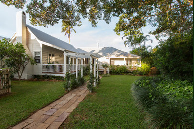 This is an example of a large traditional one-storey white house exterior in Brisbane with wood siding, a gable roof and a metal roof.