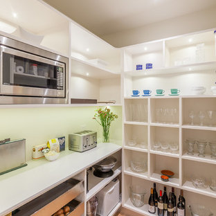 Inspiration pour une arrière-cuisine ethnique en L de taille moyenne avec un évier encastré, un placard sans porte, des portes de placard blanches, un plan de travail en quartz modifié, une crédence verte, une crédence en feuille de verre, un électroménager en acier inoxydable, un sol en bois clair et un îlot central.