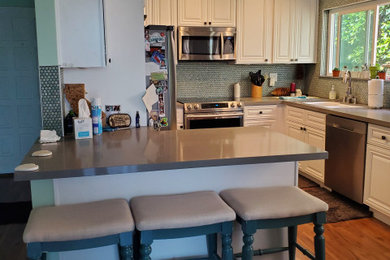 Small beach style u-shaped medium tone wood floor and brown floor eat-in kitchen photo in San Diego with an undermount sink, raised-panel cabinets, white cabinets, quartzite countertops, green backsplash, glass tile backsplash, stainless steel appliances, an island and gray countertops