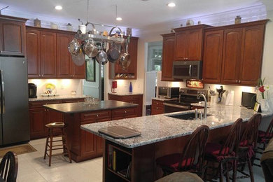 Inspiration for a timeless l-shaped ceramic tile and white floor kitchen remodel in Tampa with a single-bowl sink, raised-panel cabinets, brown cabinets, marble countertops, white backsplash and an island