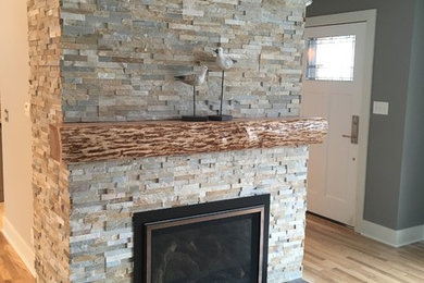 Family room - light wood floor family room idea in Grand Rapids with a standard fireplace and a stone fireplace