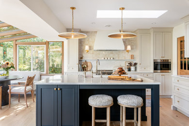 Inspiration for a large transitional l-shaped light wood floor open concept kitchen remodel in Vancouver with an undermount sink, shaker cabinets, green cabinets, marble countertops, white backsplash, marble backsplash, stainless steel appliances, an island and white countertops