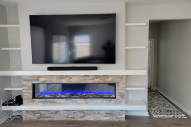 Ejemplo de sala de estar tradicional con piedra de revestimiento y televisor colgado en la pared