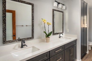 Inspiration for a mid-sized transitional master double-sink, vinyl floor and brown floor alcove shower remodel in Los Angeles with shaker cabinets, brown cabinets, quartz countertops, a hinged shower door, white countertops, a built-in vanity, a two-piece toilet, gray walls and an undermount sink