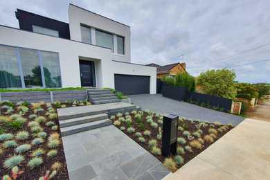 Photo of a large modern front yard full sun formal garden for spring in Melbourne with a garden path and natural stone pavers.