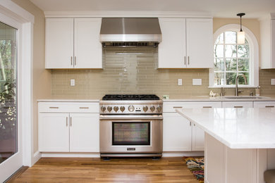 Example of a large classic galley medium tone wood floor and brown floor eat-in kitchen design in Boston with a drop-in sink, shaker cabinets, white cabinets, quartzite countertops, beige backsplash, glass tile backsplash, stainless steel appliances, an island and white countertops