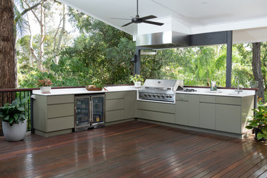 This is an example of a mid-sized modern backyard and first floor deck in Brisbane with an outdoor kitchen, a roof extension and mixed railing.