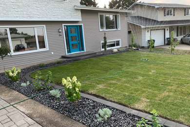 Design ideas for a large full sun front yard stone retaining wall landscape in Edmonton.
