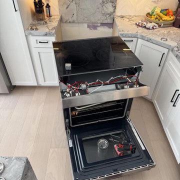 Range repair in Miami — slide-in range with the cooktop lifted and the oven door