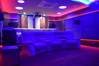 Foto de cine en casa cerrado contemporáneo grande con paredes beige, moqueta, pantalla de proyección y suelo rojo