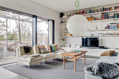 Inspiration for a mid-sized scandinavian enclosed family room in Stockholm with white walls, concrete floors, no fireplace, a freestanding tv and grey floor.
