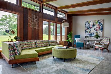 Example of a mid-century modern gray floor, exposed beam and wood wall living room design in Nashville with gray walls