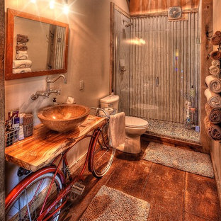 Cette photo montre une salle de bain montagne de taille moyenne avec un placard sans porte, des portes de placard beiges, un WC séparé, un carrelage gris, carrelage en métal, un mur beige, béton au sol, une vasque, un plan de toilette en bois, un sol marron, une cabine de douche à porte battante et un plan de toilette beige.