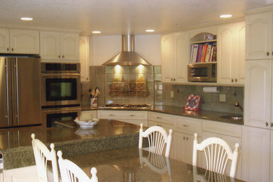 Open concept kitchen - mid-sized traditional l-shaped open concept kitchen idea in Orange County with an undermount sink, raised-panel cabinets, white cabinets, granite countertops, beige backsplash, stone tile backsplash, stainless steel appliances and an island