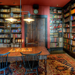 Bild på ett rustikt arbetsrum, med röda väggar, ett fristående skrivbord, mörkt trägolv och ett bibliotek