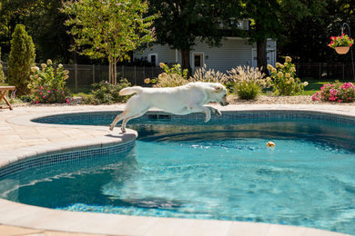 Foto de piscina tradicional de tamaño medio a medida en patio trasero con adoquines de hormigón