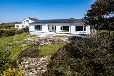 Imagen de fachada de casa blanca y negra contemporánea de tamaño medio de una planta con revestimiento de estuco, tejado a dos aguas y tejado de varios materiales