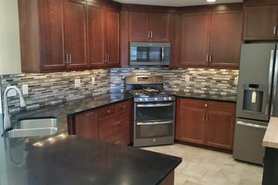 Inspiration for a mid-sized mediterranean u-shaped travertine floor enclosed kitchen remodel in Other with a double-bowl sink, shaker cabinets, medium tone wood cabinets, quartz countertops, multicolored backsplash, matchstick tile backsplash, stainless steel appliances and an island