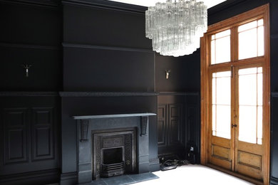 Inspiration for a large timeless enclosed light wood floor and white floor living room remodel in Los Angeles with black walls, a standard fireplace, a wood fireplace surround and no tv
