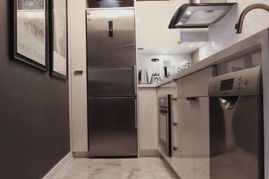 This is an example of a small modern l-shaped kitchen in Chicago with an undermount sink, white cabinets, solid surface benchtops, white splashback, porcelain splashback, stainless steel appliances, marble floors, white floor and white benchtop.