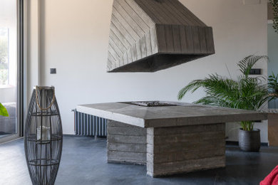 Diseño de salón industrial con chimeneas suspendidas, marco de chimenea de hormigón y suelo gris