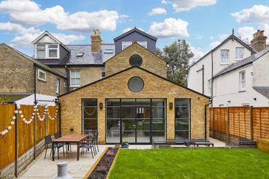 Mittelgroße, Dreistöckige Industrial Doppelhaushälfte mit gelber Fassadenfarbe, Satteldach, Ziegeldach und schwarzem Dach in Surrey