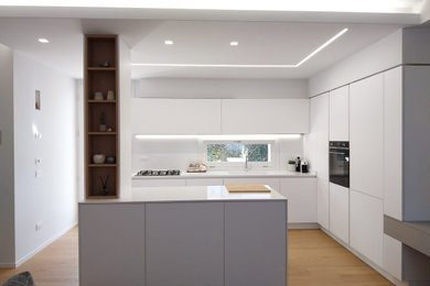 Esempio di una cucina moderna di medie dimensioni con lavello sottopiano, ante lisce, ante bianche, top in quarzo composito, paraspruzzi bianco, elettrodomestici neri, top bianco e soffitto ribassato