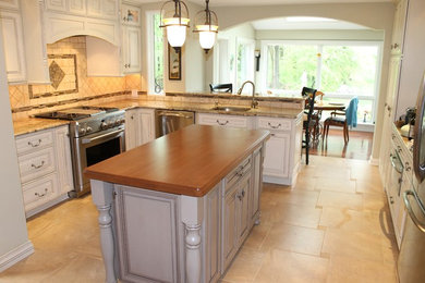 Example of a mid-sized classic l-shaped porcelain tile eat-in kitchen design in Philadelphia with an undermount sink, recessed-panel cabinets, white cabinets, granite countertops, beige backsplash, stone tile backsplash, stainless steel appliances and an island