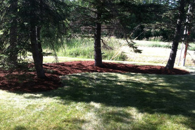 Photo of a mid-sized modern partial sun backyard mulch landscaping in Burlington for spring.