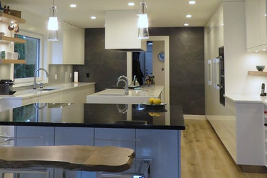 Trendy u-shaped light wood floor kitchen photo in Vancouver with an undermount sink, flat-panel cabinets, white cabinets, quartzite countertops, white backsplash and two islands