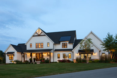 Inspiration for a huge farmhouse white two-story wood and board and batten exterior home remodel in Milwaukee with a mixed material roof and a black roof