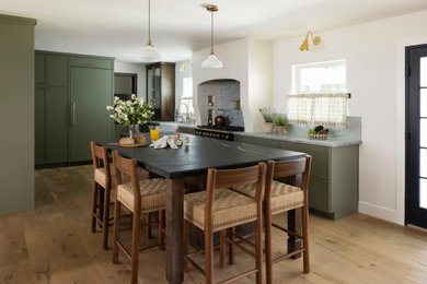 Example of a mid-sized tuscan u-shaped light wood floor open concept kitchen design in Orange County with a farmhouse sink, shaker cabinets, green cabinets, quartzite countertops, multicolored backsplash, stone slab backsplash, paneled appliances, an island and multicolored countertops