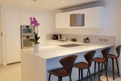 Inspiration for a medium sized contemporary u-shaped open plan kitchen in London with a single-bowl sink, flat-panel cabinets, white cabinets, quartz worktops, porcelain flooring and beige floors.