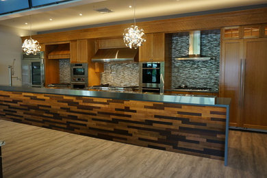 This is an example of an expansive transitional single-wall kitchen in Boston with an integrated sink, medium wood cabinets, granite benchtops, metallic splashback, stone tile splashback, stainless steel appliances, light hardwood floors and with island.