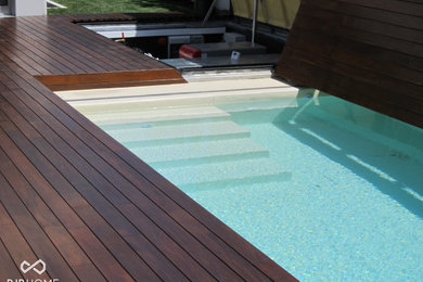 Pool - large modern custom-shaped pool idea in Miami with decking