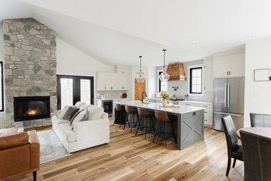 Large cottage l-shaped laminate floor, beige floor and vaulted ceiling open concept kitchen photo in Ottawa with a farmhouse sink, shaker cabinets, white cabinets, quartz countertops, white backsplash, porcelain backsplash, stainless steel appliances, an island and white countertops