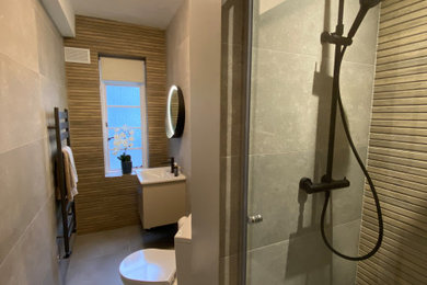 Photo of a small contemporary ensuite bathroom in London with flat-panel cabinets, a walk-in shower, a one-piece toilet, grey tiles, porcelain tiles, a single sink and a floating vanity unit.