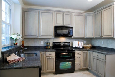Mid-sized transitional u-shaped porcelain tile kitchen photo in Philadelphia with an undermount sink, raised-panel cabinets, gray cabinets, quartz countertops, gray backsplash, porcelain backsplash, black appliances and no island