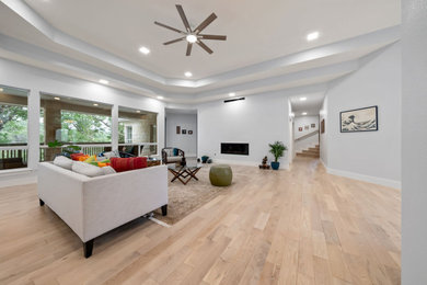 Inspiration for a huge modern formal and open concept light wood floor and tray ceiling living room remodel in Austin with gray walls, a ribbon fireplace, a plaster fireplace and no tv